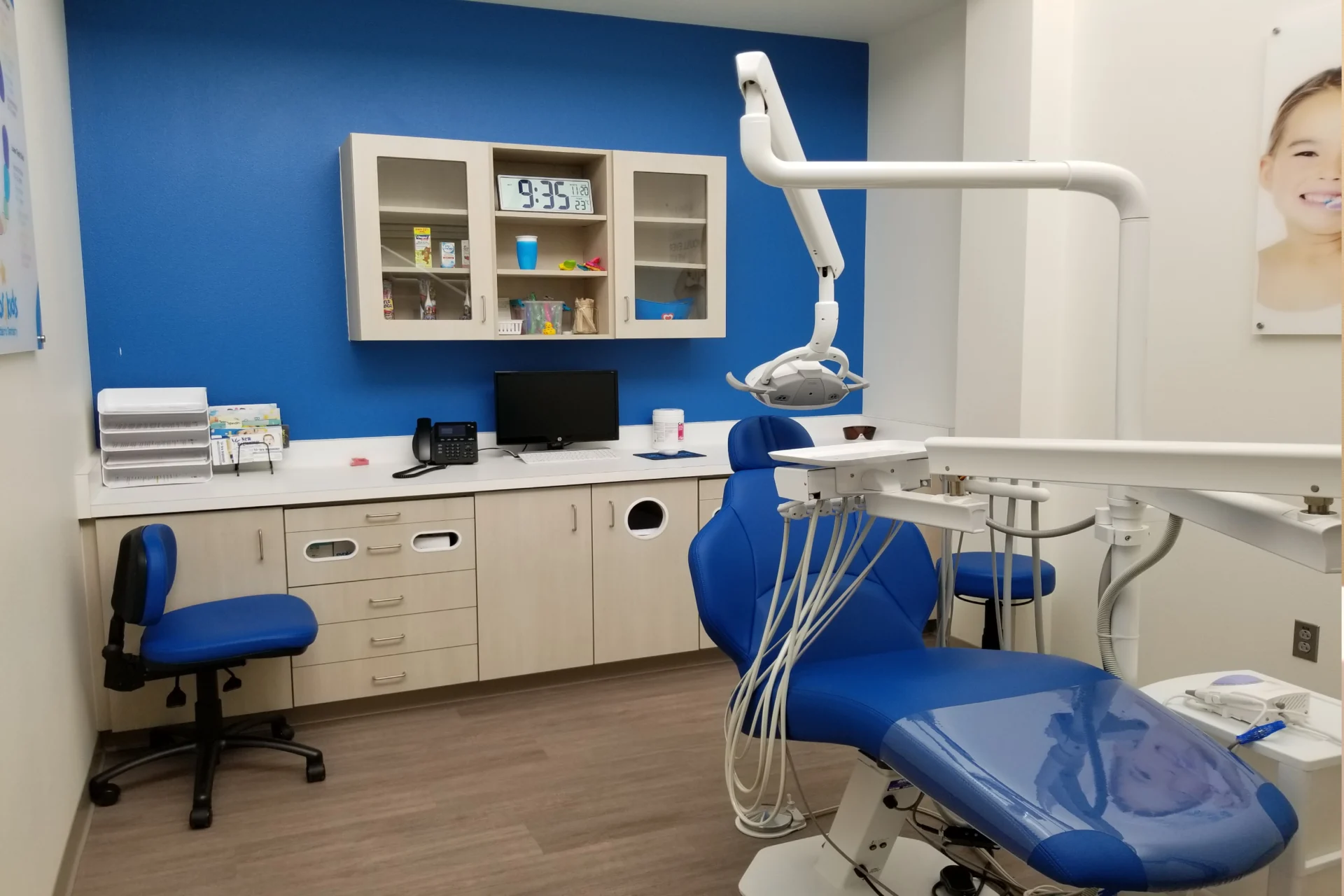 A dentist 's office with blue walls and white cabinets.