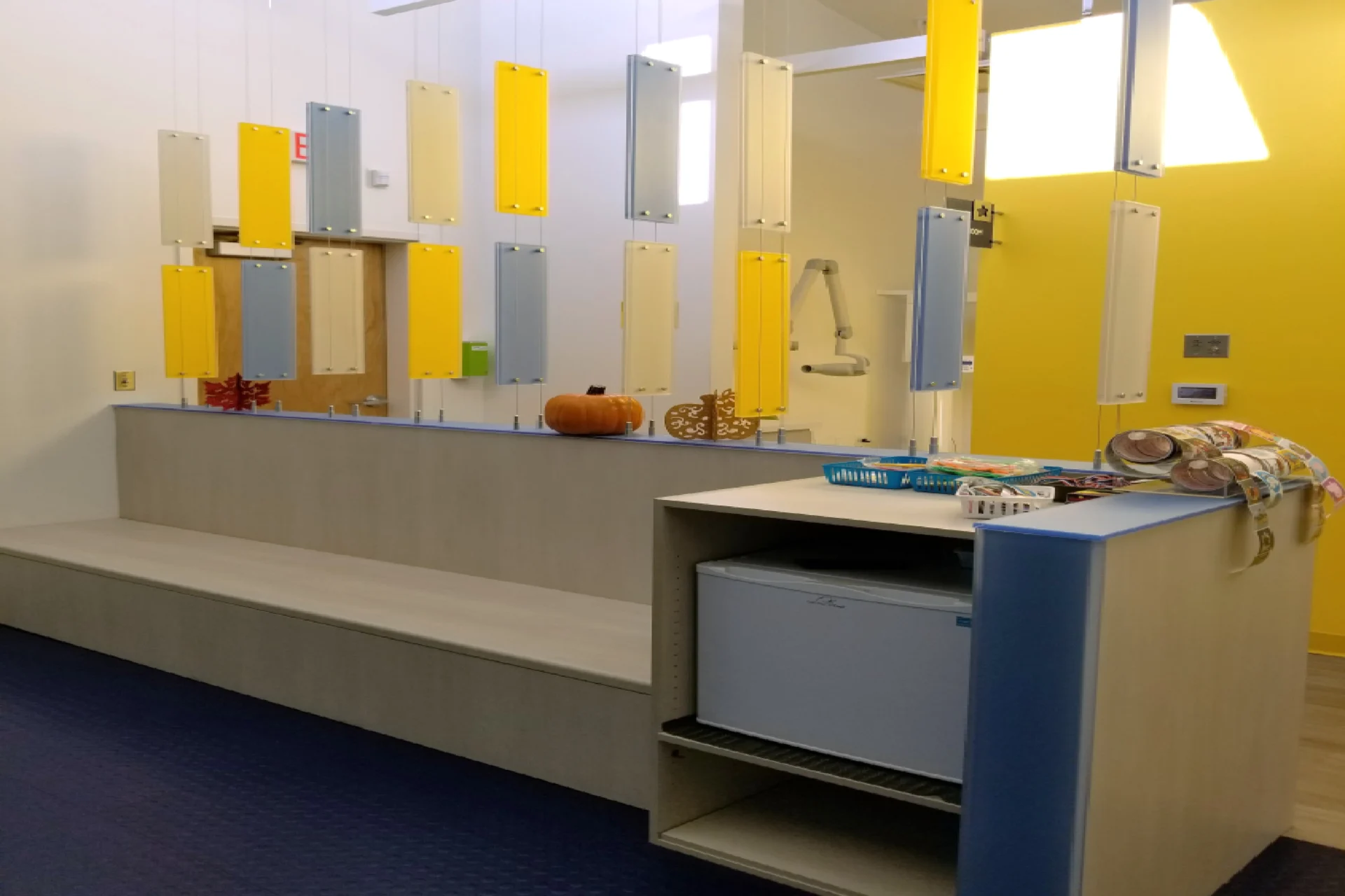 A bathroom with yellow and white walls, a bench and a sink.