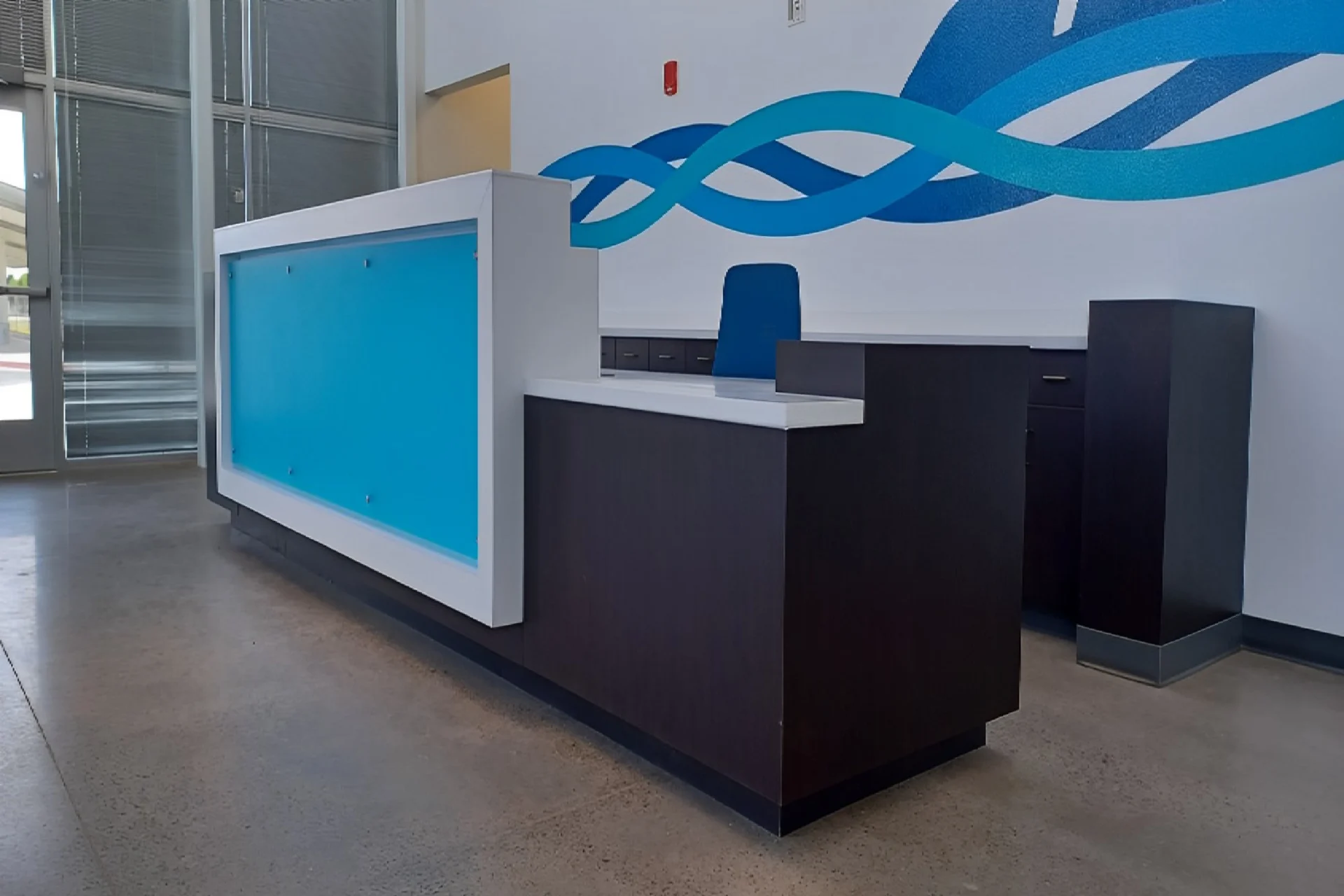 A blue and white reception desk with a large wave in the background.