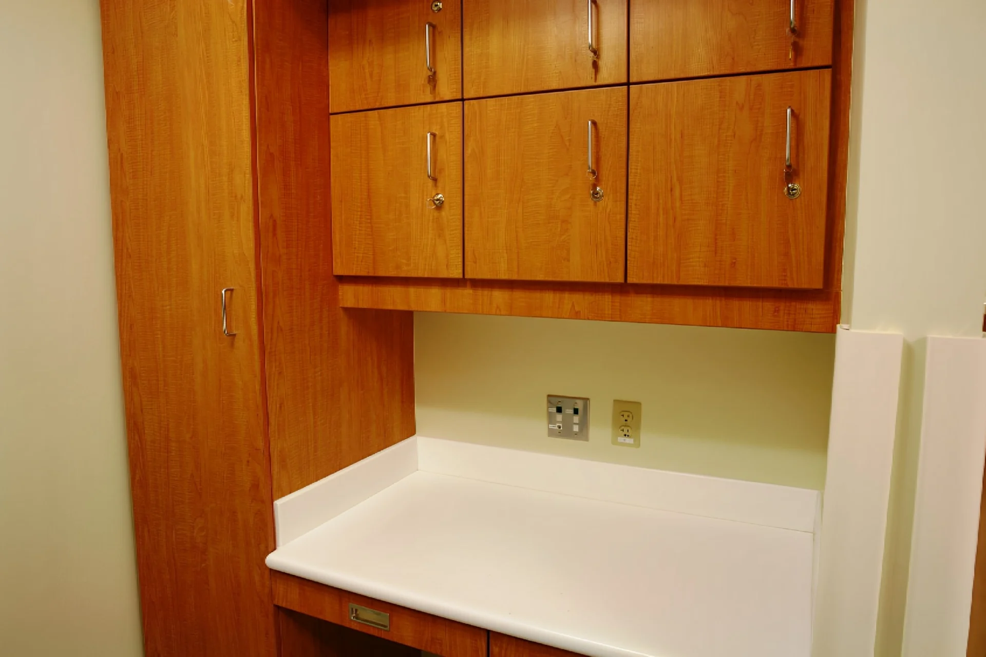 A kitchen with wooden cabinets and white counter tops.