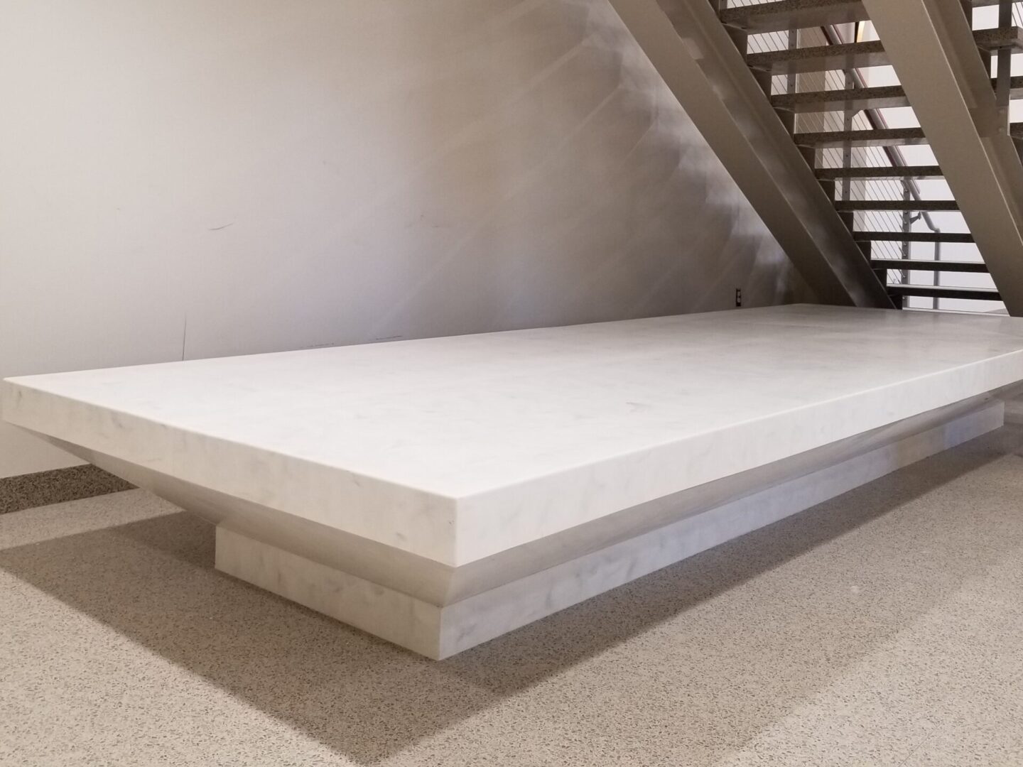 A white slab of concrete in front of stairs.