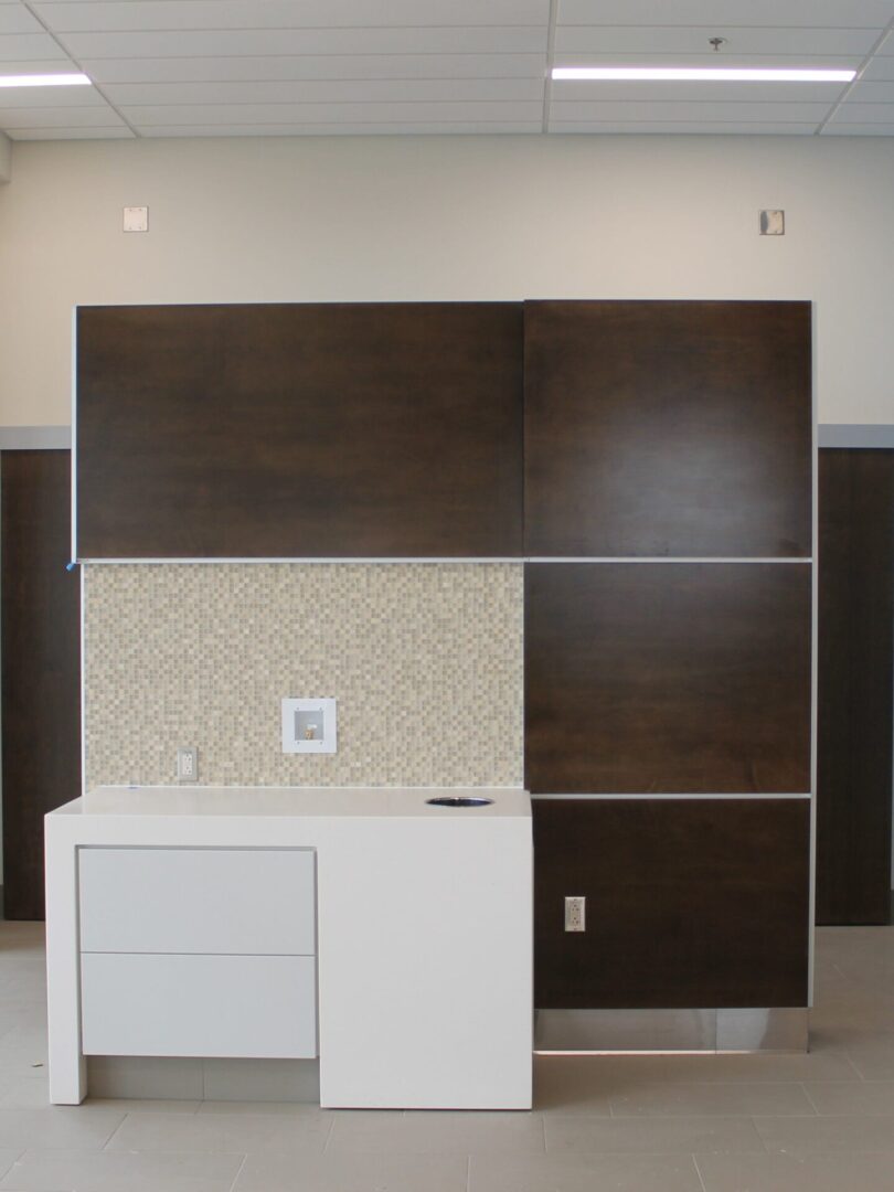 A kitchen with brown and white cabinets and a wall.